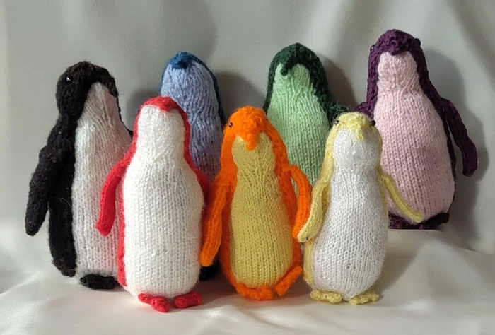 Sept manchots en tricot : noir, bleu, vert; violet, rouge, orange et jaune